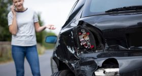 Unhappy Female Driver With Damaged Car After Accident Calling Insurance Company On Mobile Phone