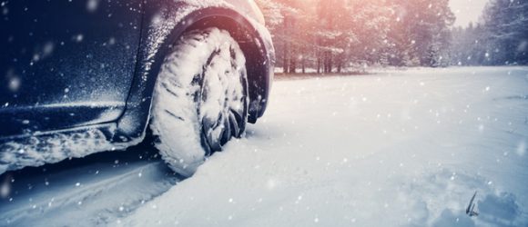 Car tires on winter road covered with snow.
