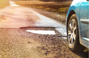 Car and winter pothole on open road