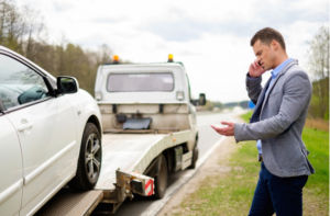 Man calling while tow truck picking up his broken car