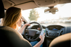 woman looking to her smartphone while driving car