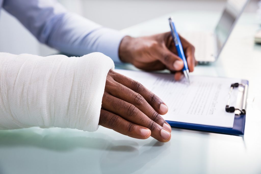 Overhead,View,Of,Injured,Man,With,Bandage,Hand,Filling,Insurance