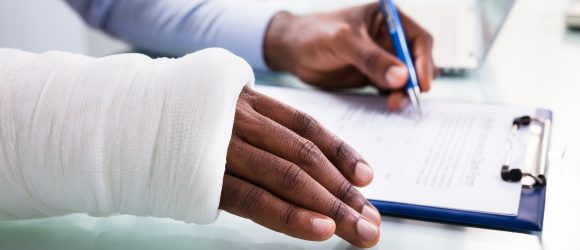 Overhead,View,Of,Injured,Man,With,Bandage,Hand,Filling,Insurance
